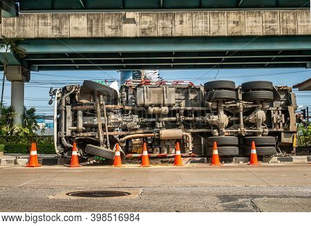 A View Of Under The Truck Carrying A Container Overturned On A Road Under A Bridge Over An Intersect