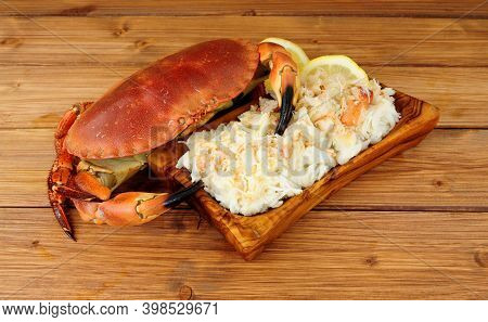 Whole Fresh Cooked Brown Crab And Fresh Meat In A Wood Dish On A Wooden Background With Lemon