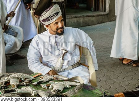 Nizwa, Oman, December 2, 2016: A vendor is selling khanjars - traditional Omani daggers - at the Friday gun market in Nizwa