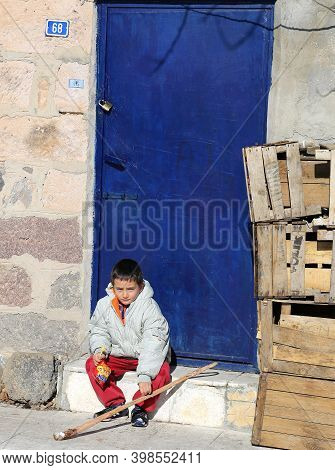 Nigde,turkey-january 15:unidentified Boy  With Lolipop And Crackers Sitting By The Blue Door.january