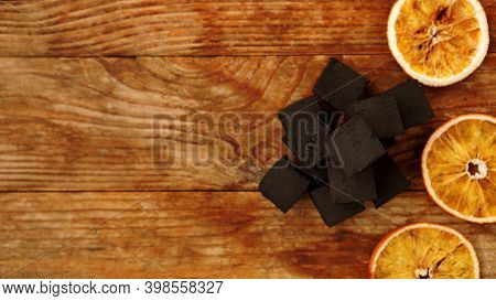 Coals For Hookah On Wooden Background With Dry Oranges. Place For Text And Top View