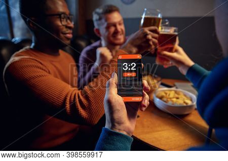 Clinking. Excited Fans In Bar With Beer And Mobile App For Betting, Score On Their Devices. Screen W