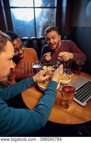 Astonished. Excited Fans In Bar With Beer And Mobile App For Betting, Score On Their Devices. Screen