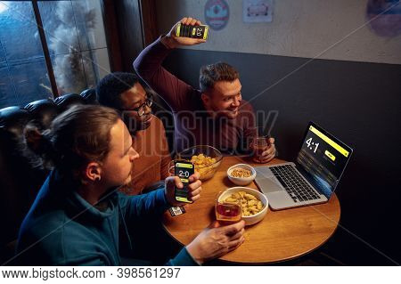 Analyzing. Excited Fans In Bar With Beer And Mobile App For Betting, Score On Their Devices. Screen 