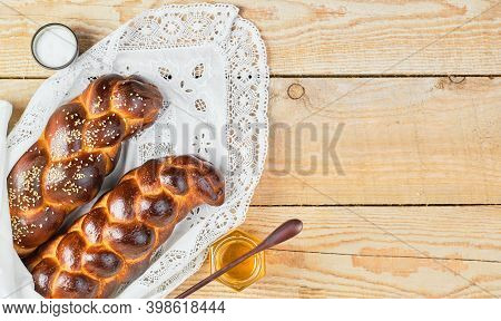 Fresh Homemade Challah With Sesame Seeds On A White Lace Napkin. Honey And Butter On The Table. Top 