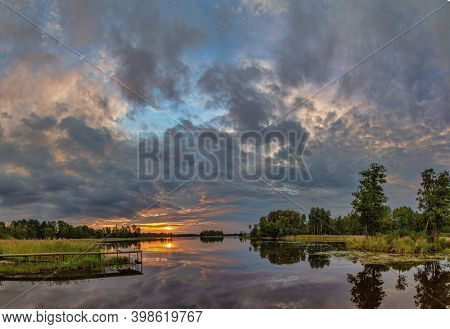 orange sunset in large clowds above river