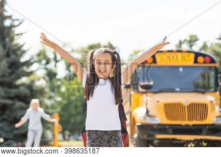 Mother Brings Her Daughter To School Near The School Bus. Back To School