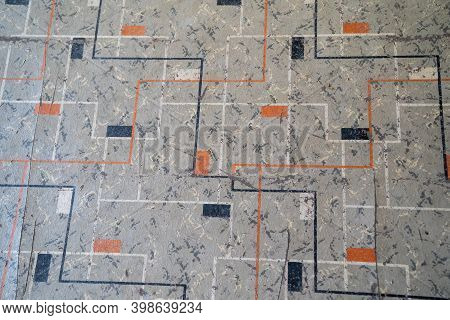 Close Up Of Old, Cracked And Peeling Linoleum With A Gray, Orange And Black Square Design
