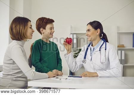 Confident Smiling Woman Pediatrician Showing Happy Heart To Positive Boy Teen Patient And His Mother