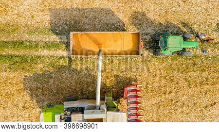 Aerial Top View Of Transshipment From Agricultural Harvester, Combine To The Trailer, Unloading Harv