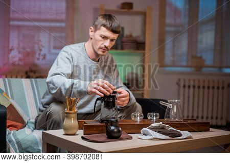 A Man Brews Chinese Tea According To An Old Oriental Recipe On A Bamboo Gongfu Tray. Adds Boiling Wa