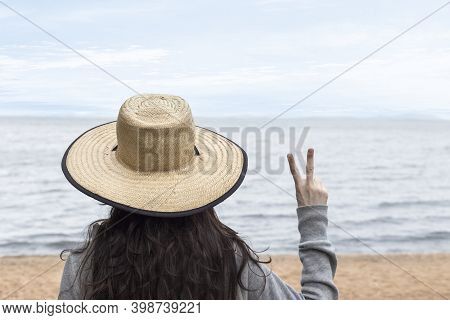 Girl In Vacation With Hat Relaxing Doing Peace And Love With Fingers - Facing The Sea - Tourism And