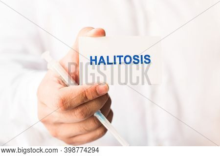 Word Halitosis On A White Background With A Syringe In Hand. Medicine Concept