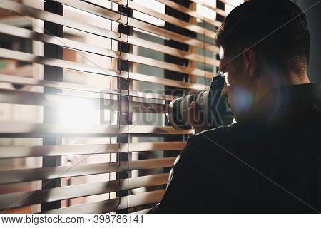 Private Detective With Camera Spying Near Window Indoors