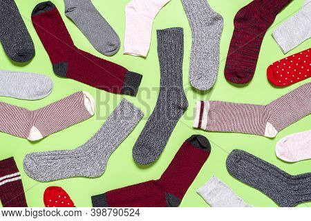 Above View With Many Socks Of Different Texture, Color And Shape On A Green Background. Flat Lay Wit