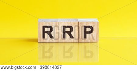Rrp - Recommended Retail Price - Word Is Made Of Wooden Building Blocks Lying On The Yellow Table