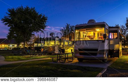 Camping In A Rv At The Rv Resort In Front Of A Water Fountain At Sunset With Lights On The Motorhome