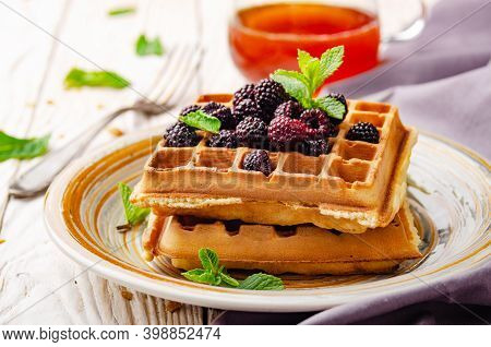 Closeup View At Belgian Waffles Served With Blackerries And Mint Leaf On White Wooden Kitchen Table 