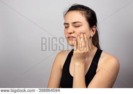 A Woman Holds A Sore Tooth With Her Hand. Dental Pain In Dentistry, Pulpitis And Tooth Decay, Nerve 