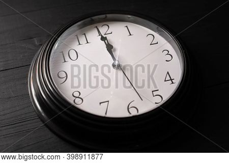 Clock On A Black Background. A Minute To Twelve.