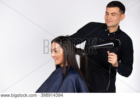 A Professional Male Hairdresser Dries A Young Womans Hair With A Foen. Gender Stereotypes. White Bac