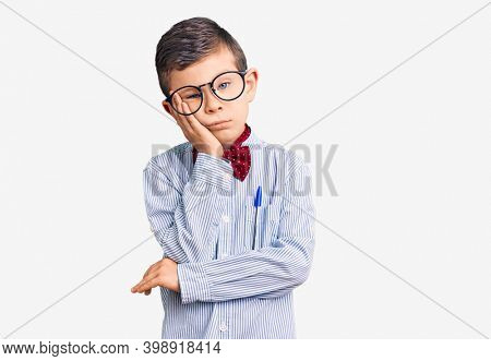 Cute blond kid wearing nerd bow tie and glasses thinking looking tired and bored with depression problems with crossed arms. 