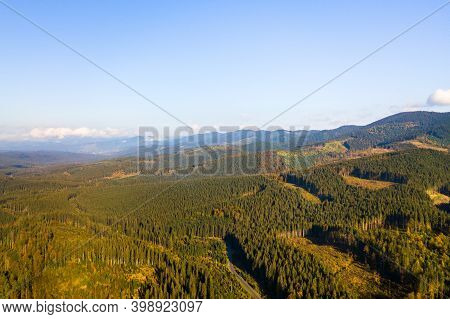 Aerial View Of Mountain Forest With Bare Deforestation Areas Of Cut Down Trees.