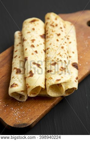 Homemade Norwegian Potato Flatbread (lefse) With Butter And Sugar On A Rustic Wooden Board On A Blac