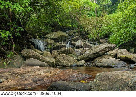 Water Cascading Down Over Pebble Rocks In Gorgeous Autumn Forest