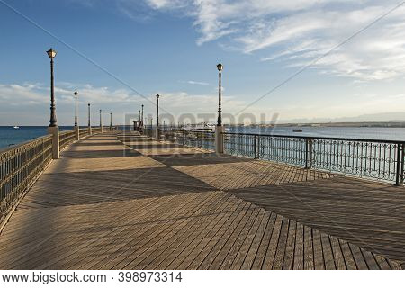 Scenic View Down A Large Wooden Jetty Pier Over Sea In Tropical Coastal Seaside Resort