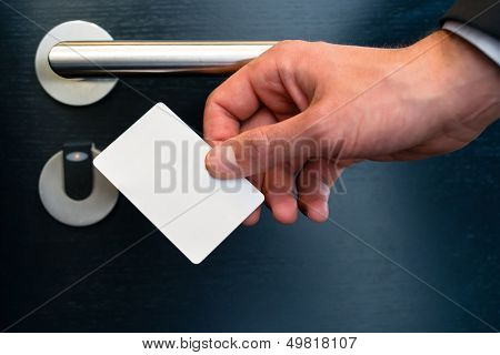 Hotel door - Young man holding a keycard in front of the electronic sensor of a room door 