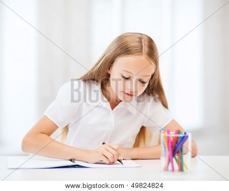 education and school concept - little student girl drawing at school