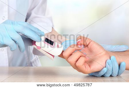 Doctor measuring pulse rate and oxygen levels, on bright background