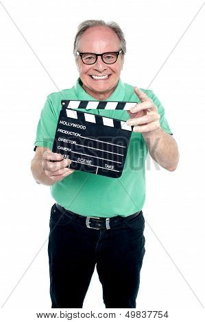 Bespectacled Elderly Man Holding A Clapperboard