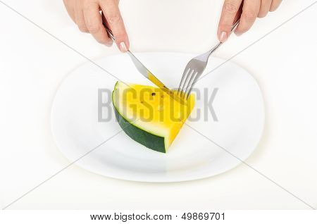Women's hands are cut off yellow watermelon