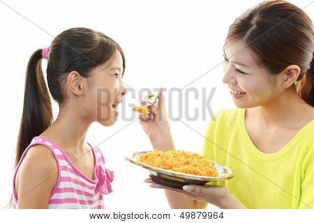 Girl eating meal with mother