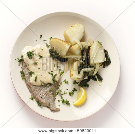 Fried and peppered escalope of veal served with  potatoes mixed with wilted chard and a creamy gravy, all garnished with chopped herbs and served with a lemon wedge, from above