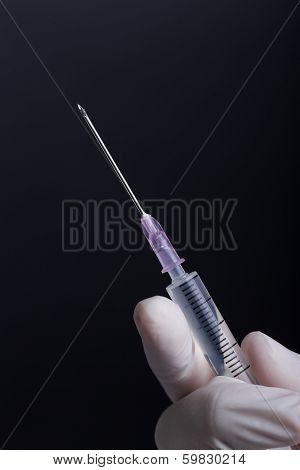 Hand in latex gloves holding syringe