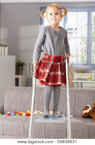Proud little girl smiling happily on top of ladder.