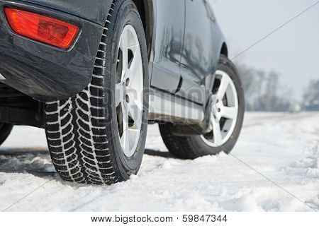 Car with winter tyres installed on light alloy wheels in snowy outdoors road