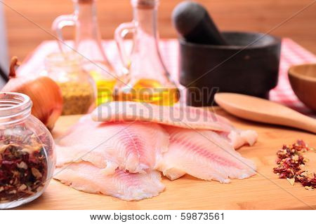 Raw fish tilapia on cutting board and spices