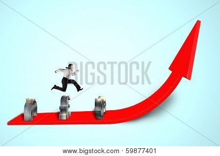 Businessman Jumping Over Money Symbols On Growing Red Arrow