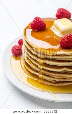 Big Pile of American  Pancakes with Raspberries, Melted Butter and Maple Syrup