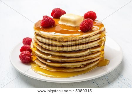 Big Pile of American  Pancakes with Raspberries, Melted Butter and Maple Syrup