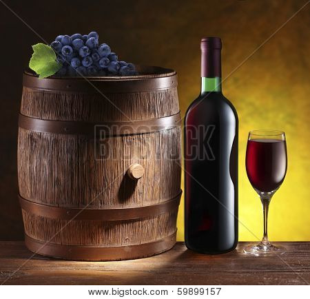 Still life with wine barrel, bottle and glass. Dark yellow background.