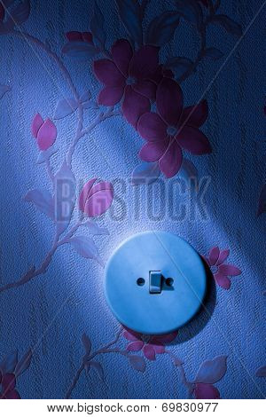an old wallpaper with light switch. symbolic photo for renovation and remodel.