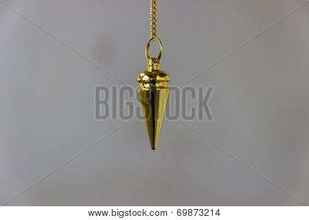 closeup picture of dowsing pendulum made of yellow metal