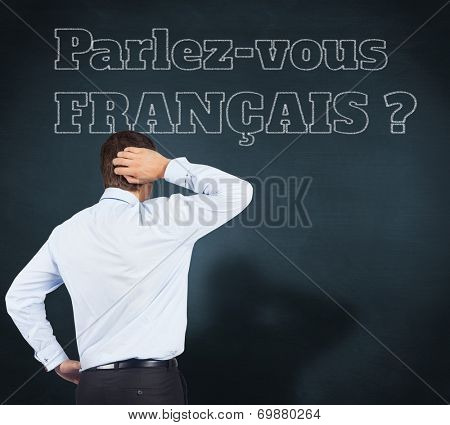 Thinking businessman scratching head against blue chalkboard, Do you speak French?