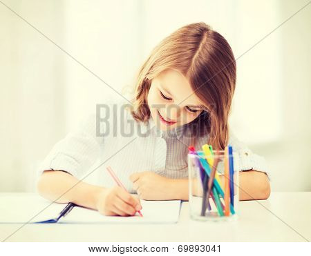 education and school concept - little student girl drawing at school