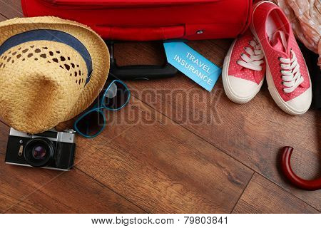 Suitcase and tourist stuff with inscription travel insurance on wooden background